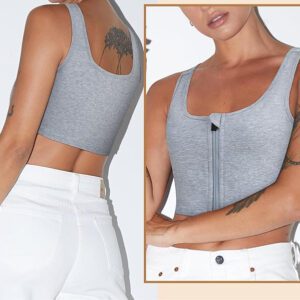 A person is wearing a light gray ftm chest binder with a zipper on the front and white pants. The image shows both the back and front views of the outfit. The person has tattoos on their arms and one on their shoulder blade.
