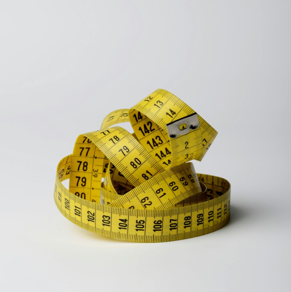 A yellow measuring tape, in a small pile on a white background