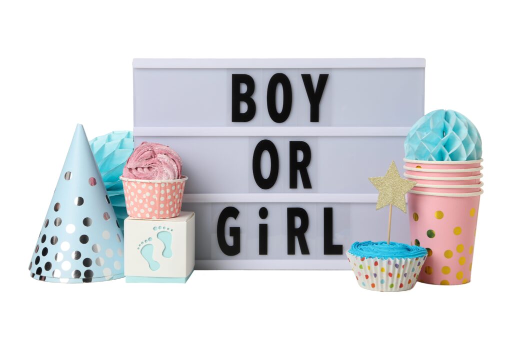 boy or girl A lightbox sign reads “BOY OR GIRL” surrounded by polka-dot party hats, cups, a cupcake, a star decoration, and baby-themed items in pastel blue and pink—highlighting the celebration of gender in a playful setting.