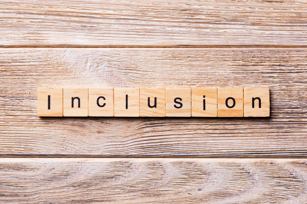 inclusion Wooden tiles spell out the word "Inclusion" on a rustic wooden surface, emphasizing the importance of belonging and acceptance across gender and trans identity.