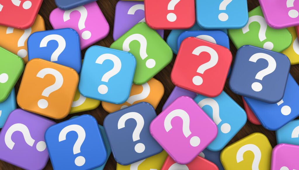 Question marks Colorful square tiles with white question marks are scattered randomly, overlapping each other. The vibrant tiles—blue, orange, green, pink, purple, and yellow—create a playful and curious atmosphere that encourages understanding and invites thoughtful questions to ask about topics such as trans men.