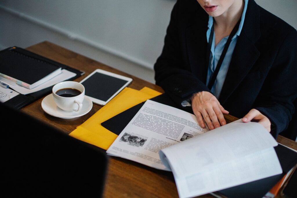 pexels-photo-5668501-5668501 High angle of crop faceless businesswoman in formal clothes sitting at table with tablet and hot coffee and looking through documents