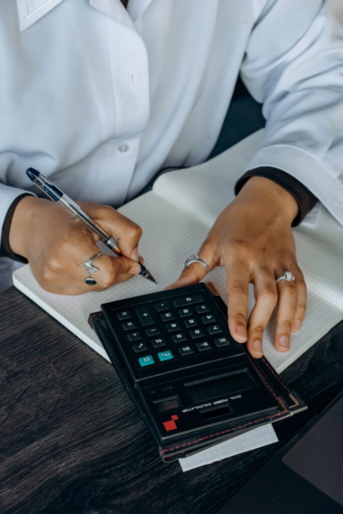 pexels-photo-8297150-8297150 Close-up of hands writing in a notebook while using a calculator. Ideal for finance and business concepts.