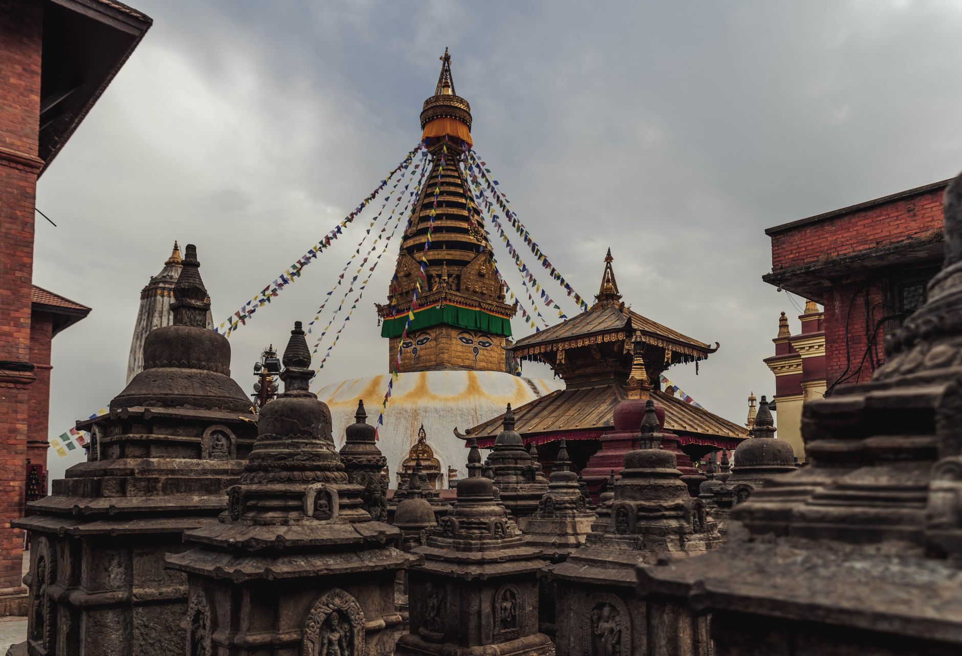 Swayambhunath Stupa in Kathmandu, Nepal, with prayer flags strung from its spire above weathered stone shrines