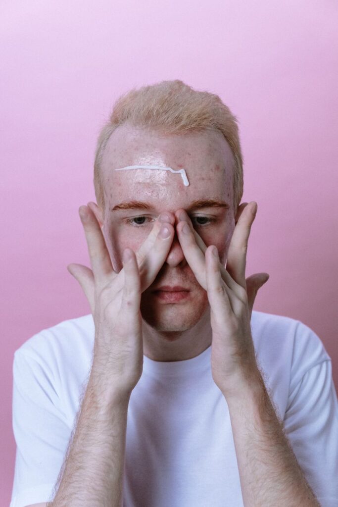 man in white crew neck shirt covering his face with his hand