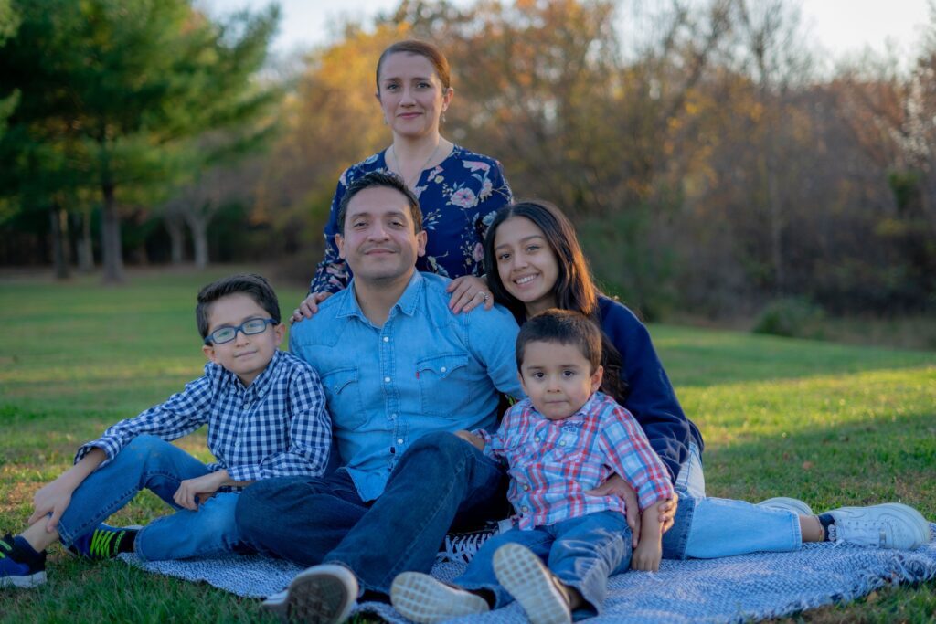 pexels-photo-5857048-5857048 A joyful family sitting together on grass in a park with warm smiles.